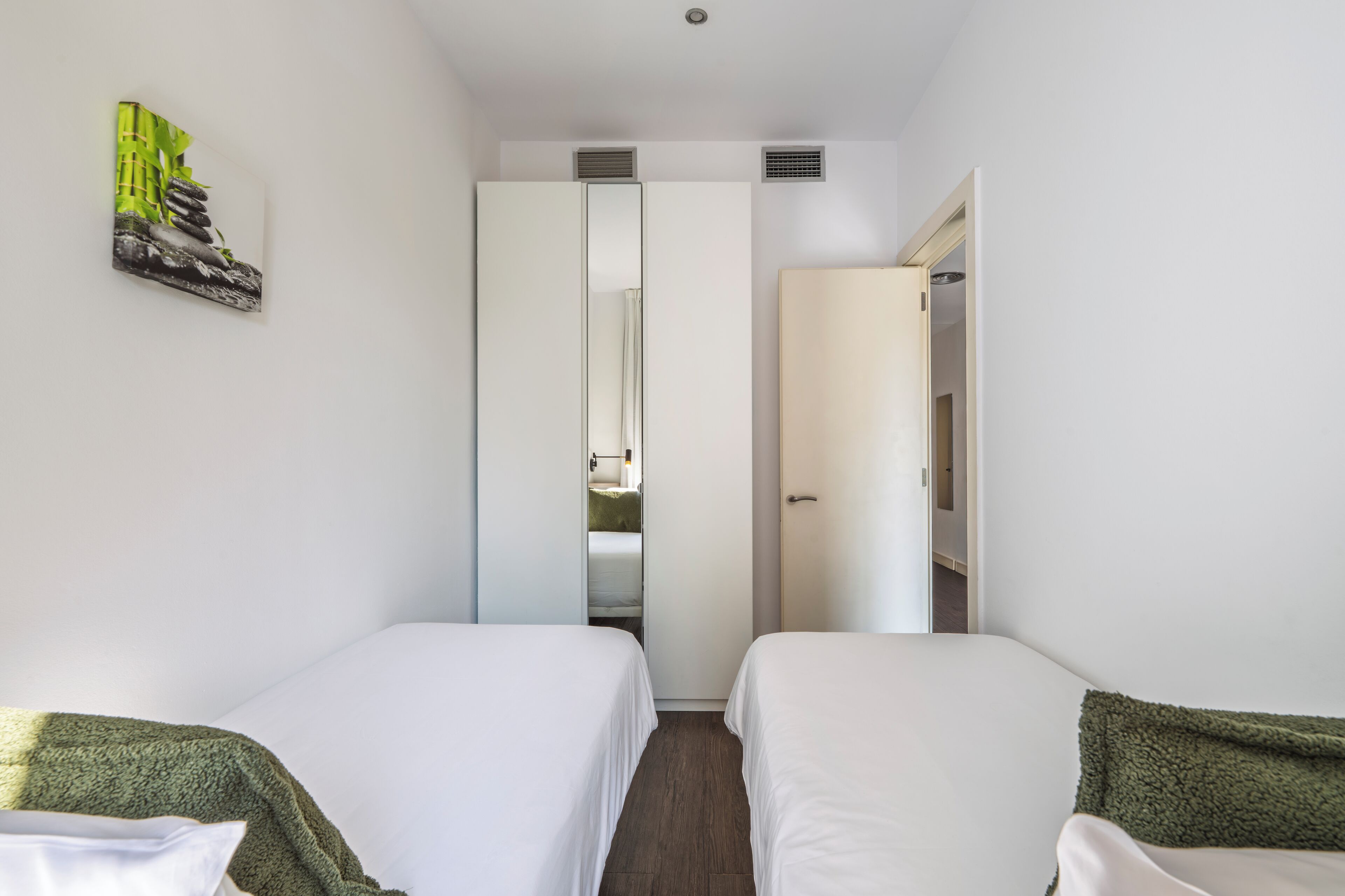 Ett hotellrum med två sängar, en garderob och en tavla på väggen.
