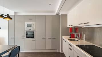 Una cocina moderna con electrodomésticos de acero inoxidable, armarios blancos y piso de madera oscura.