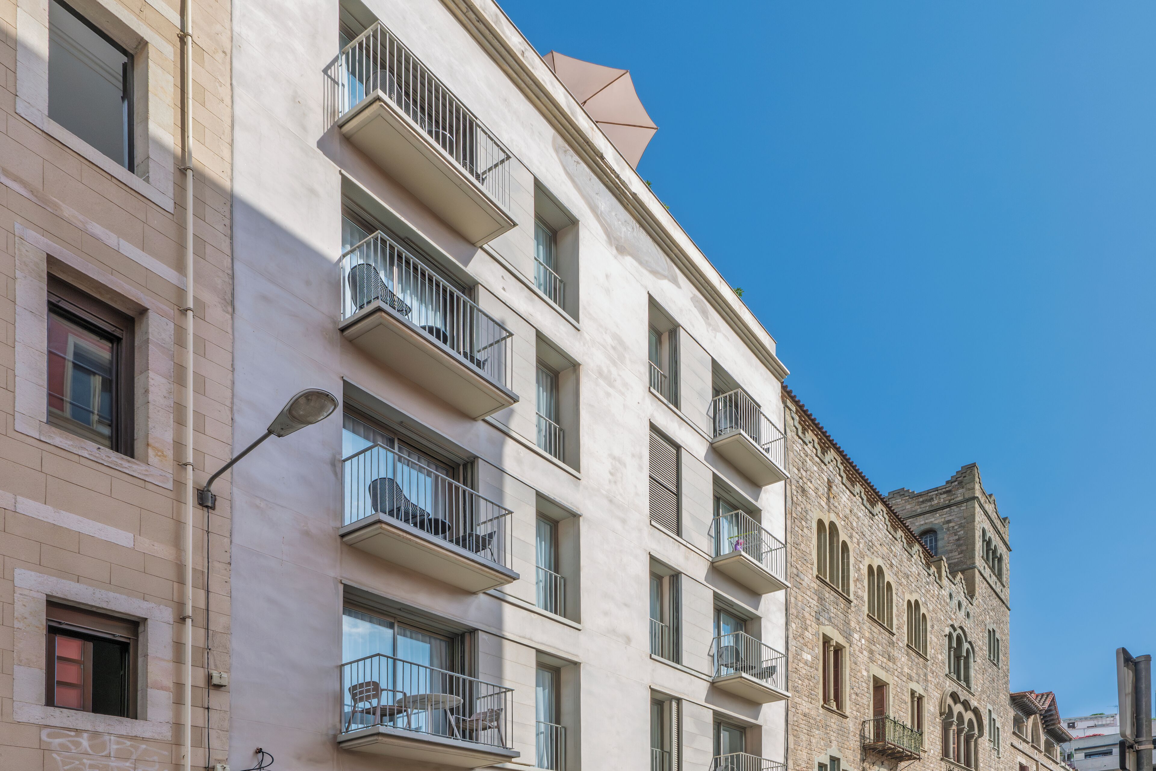 Un edificio de varios pisos con balcones, ventanas amplias y un cielo azul despejado.