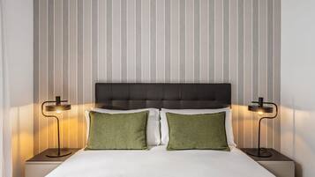 A neatly made bed with two pillows, a headboard, and two bedside lamps.