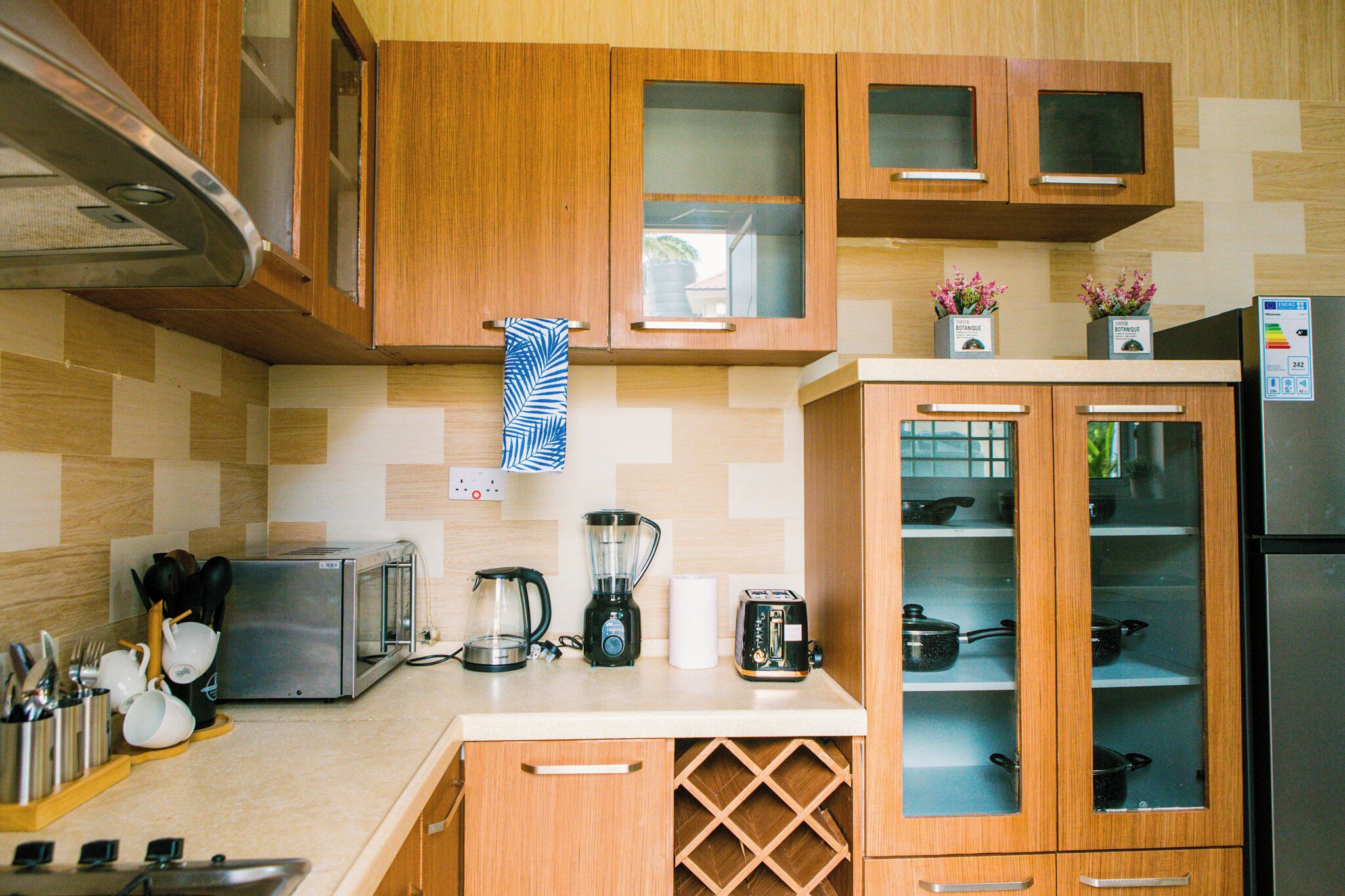 A kitchen with wooden cabinets, a toaster, a blender, and a refrigerator.