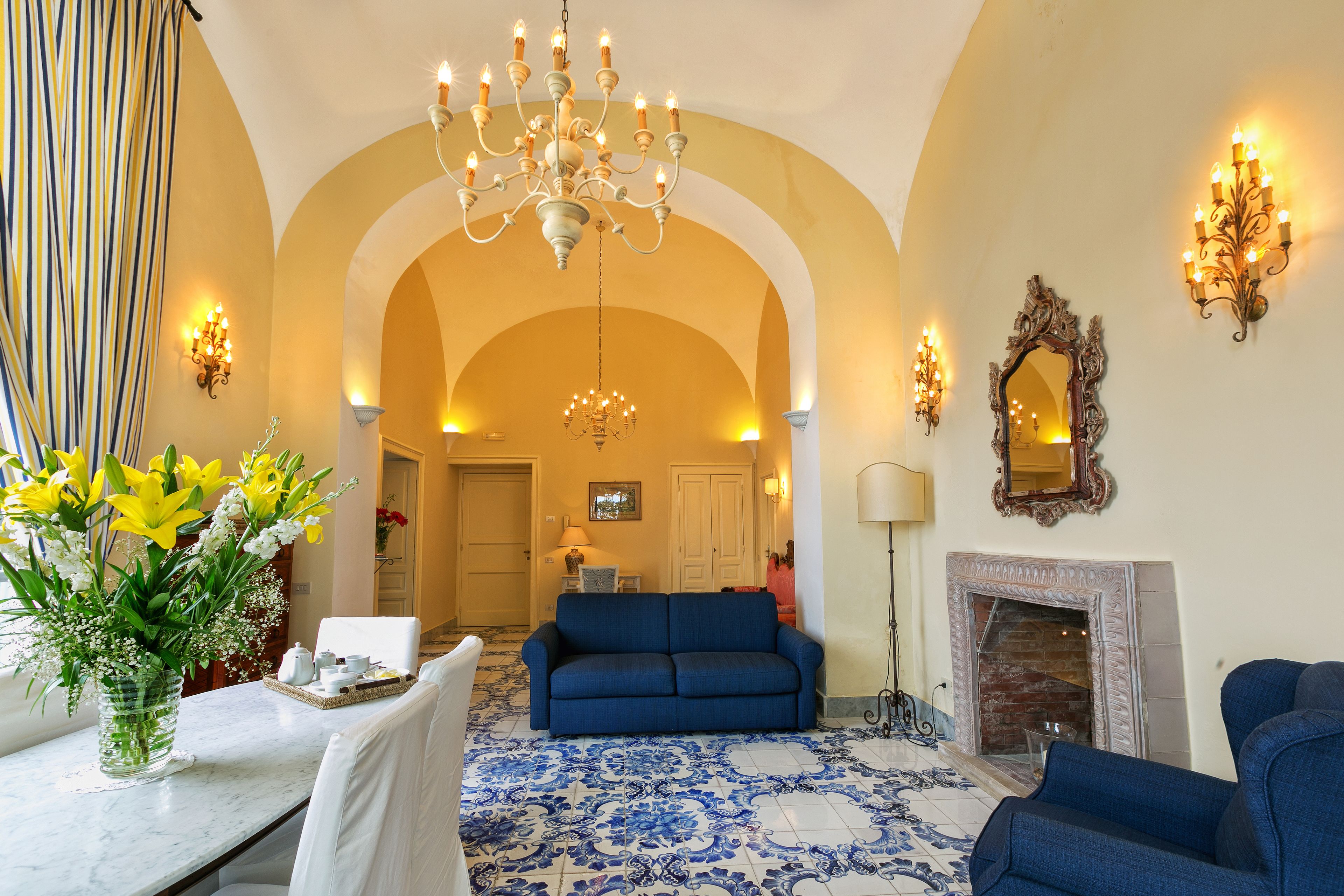A living room with a blue sofa, a chandelier, and a fireplace.