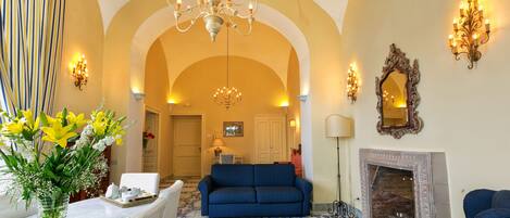 A living room with a blue sofa, a chandelier, and a fireplace.