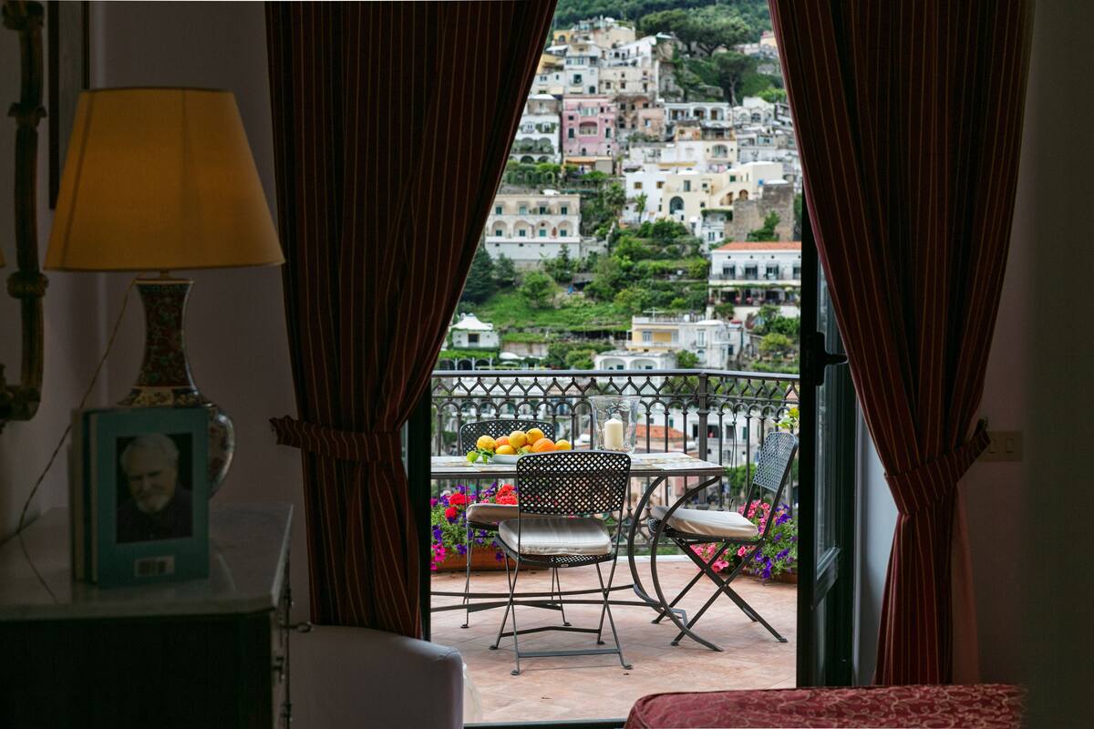 Un balcon avec une table, des chaises et un vase de fleurs.