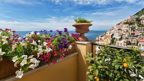 Un balcon agrémenté de fleurs aux couleurs vives, offrant une vue sur une ville côtière.