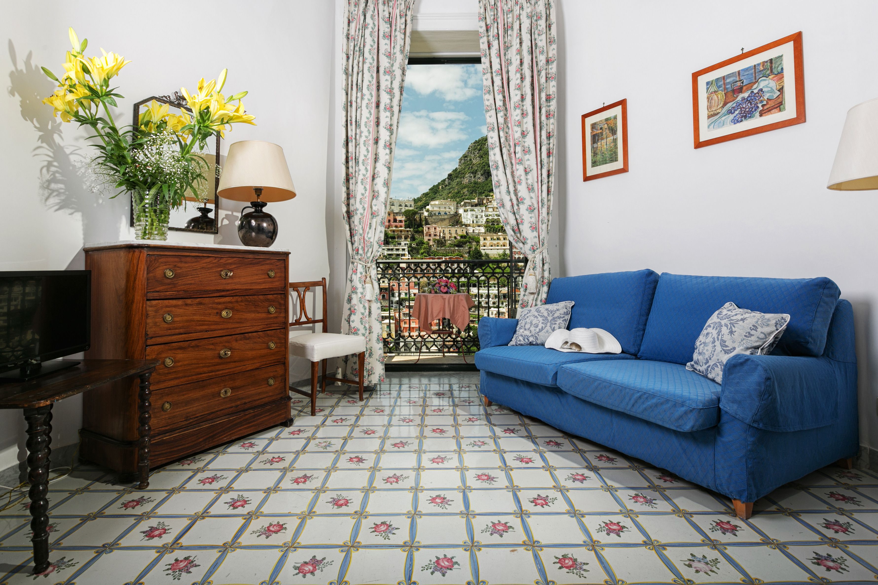 Una sala de estar con un sofá azul, un aparador de madera y un televisor.
