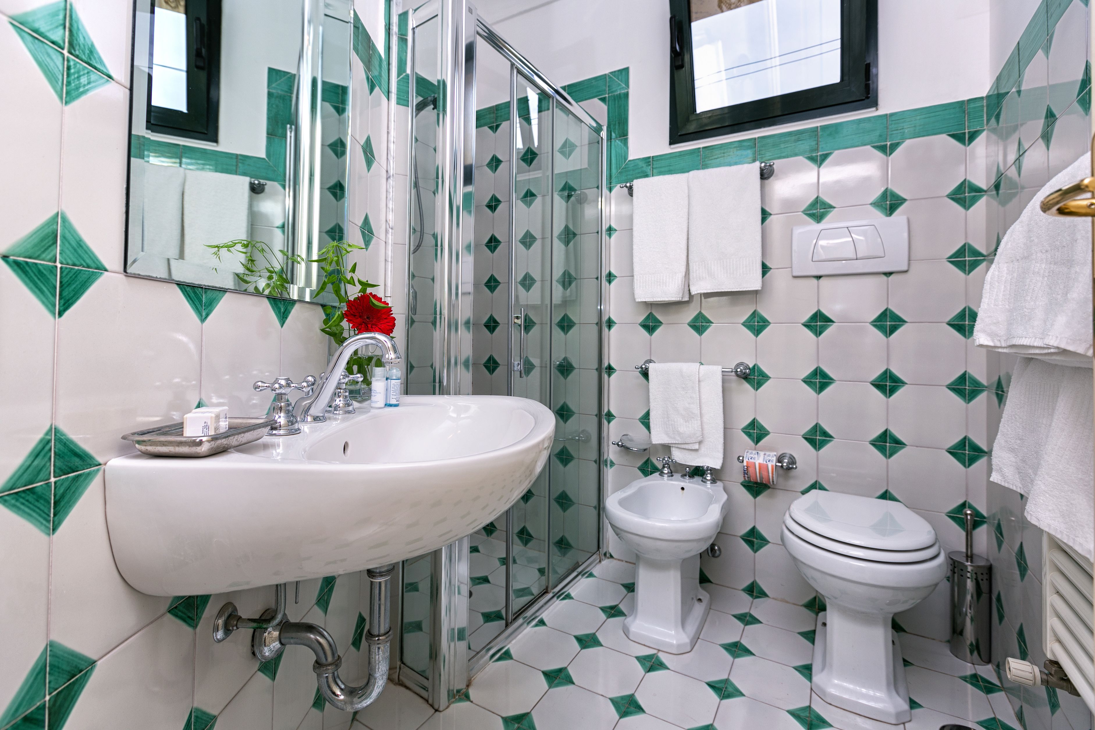 A bathroom with a white sink, a bidet, a toilet, and a shower enclosure.
