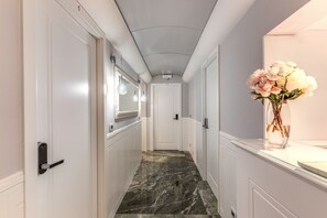 A hallway with white doors, a marble floor, and a vase with flowers on a counter. - Rome55 - Piazza di Spagna (Rome)
