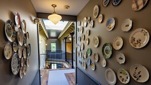 A hallway with a collection of plates on the walls, leading to a staircase. - The Porches Inn at Mass MoCA (North Adams)
