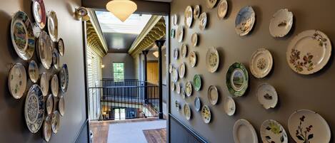 A hallway with a collection of plates on the walls, leading to a staircase.