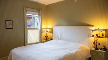 Una cama bien hecha en una habitación de hotel, con dos mesitas de noche, cada una con una lámpara y un teléfono.
