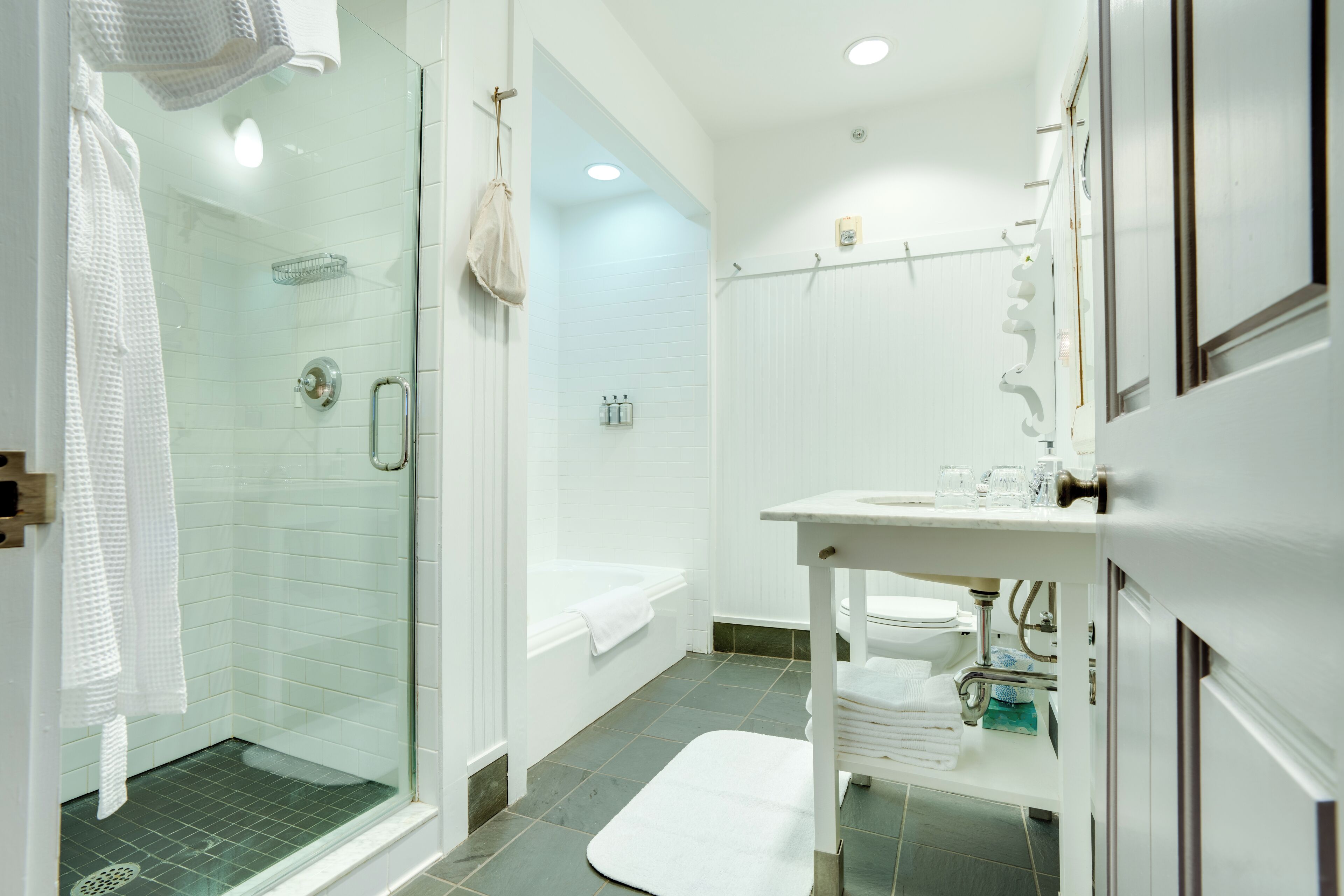 Ein modernes Badezimmer mit einer gläsernen Duschkabine, einer weißen Badewanne und einem Waschbecken mit Spiegel.