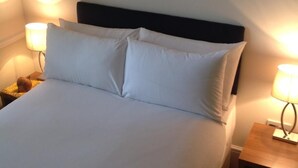 A neatly made bed with white linens and two pillows, flanked by bedside tables with lamps, in a room with a simple, clean design. - The Stag Enfield (Enfield)