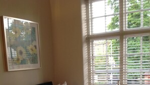A neatly made bed with white linens, a green throw blanket, and two folded towels on a green mat. A framed floral artwork hangs on the wall above the bed. - The Stag Enfield (Enfield)