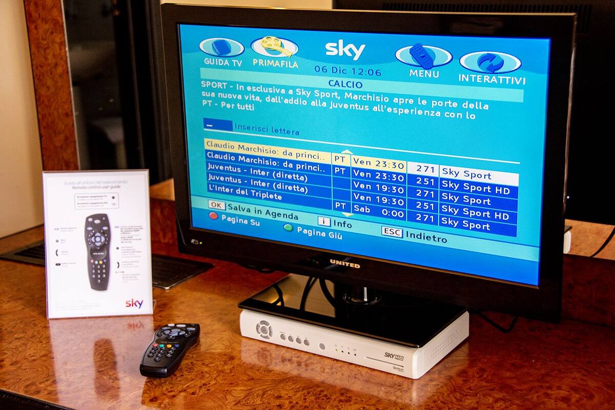 Ein Sky HD Fernseher auf einem Holztisch mit einer Fernbedienung daneben.