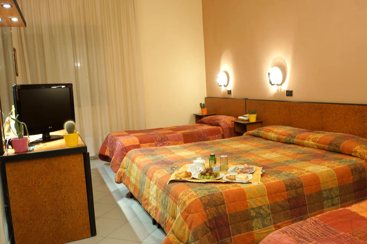 Ein Hotelzimmer mit zwei Betten, einem Schreibtisch mit Computer und einem Frühstücksbrettchen auf dem Bett.