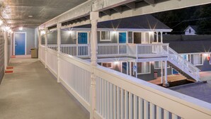 Ein Motel mit überdachtem Gang, mehreren Zimmern mit blauen Türen und einer Treppe, die zu einer oberen Ebene führt.