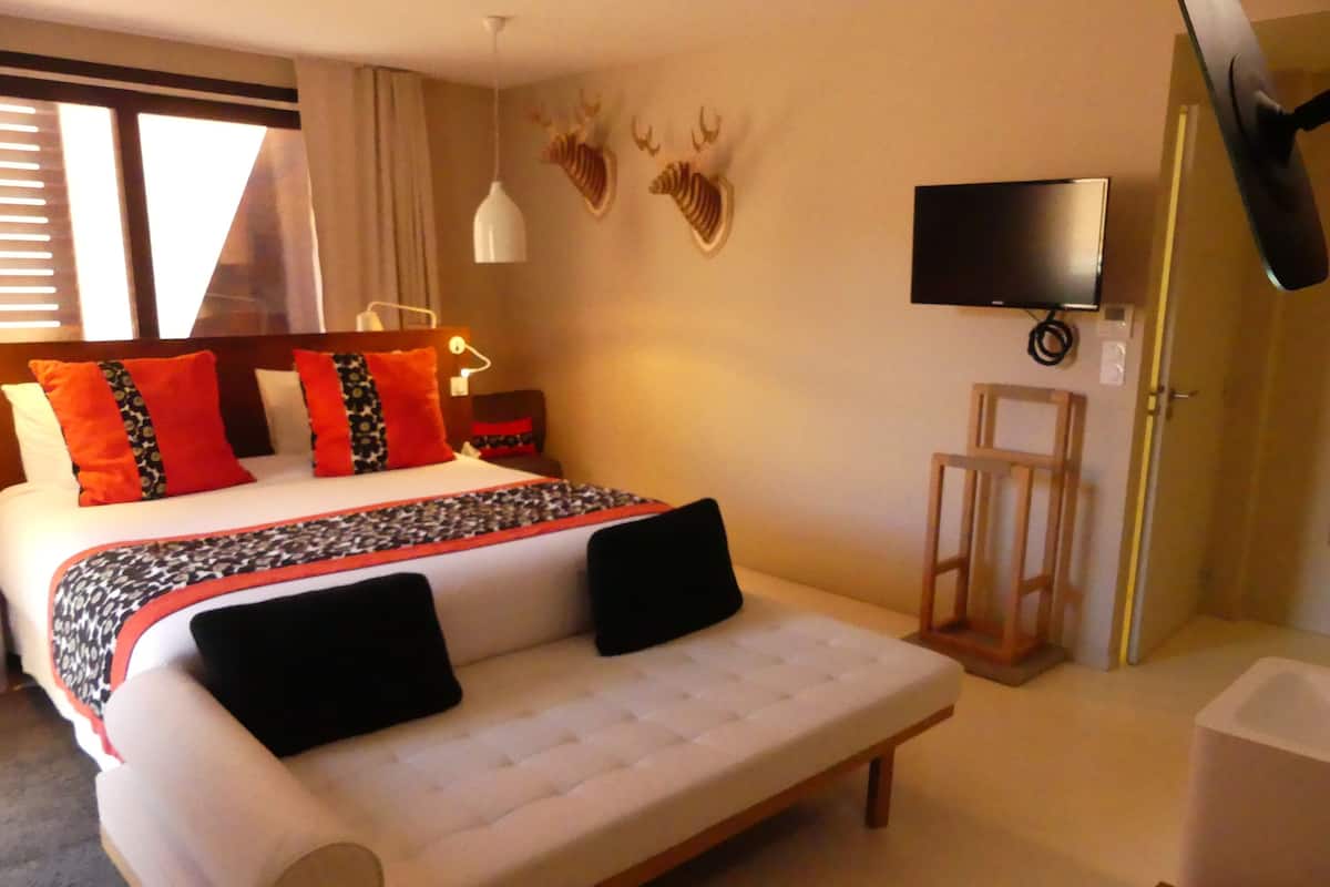 Habitación de hotel con cama, sofá, televisión y un ciervo montado en la pared.