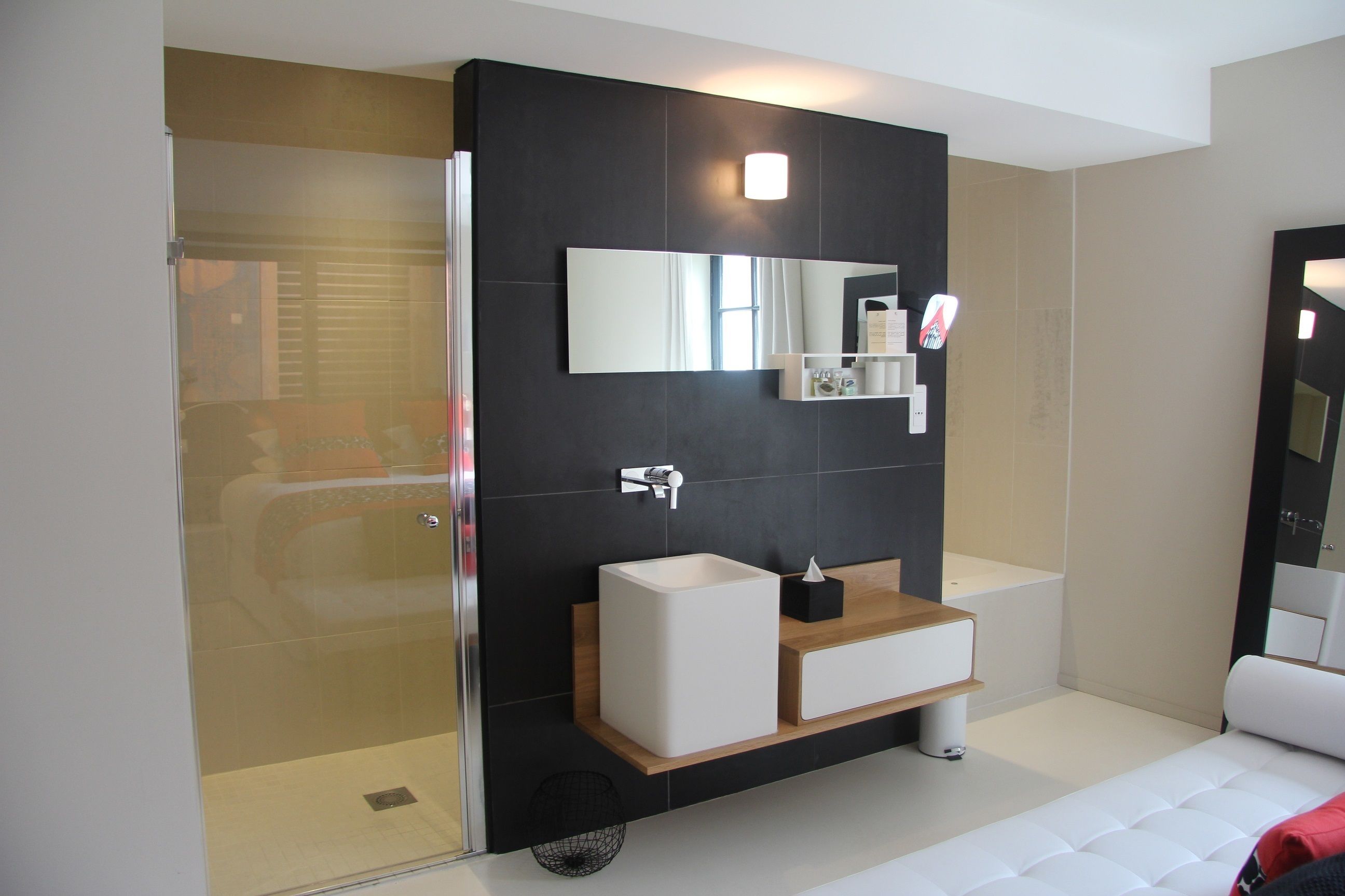 Un baño moderno con cabina de ducha de vidrio, un lavabo blanco y un espejo grande sobre el mueble.