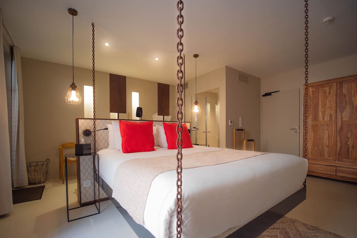Un dormitorio espacioso con una cama grande, un armario de madera y un espejo sobre la cama.
