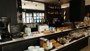 Un buffet de petit-déjeuner proposant une variété d’aliments, une machine à café et un bar avec des bouteilles.