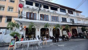 A two-story building with a restaurant on the ground floor. There are outdoor tables and chairs set up for dining. - Steve Lady Hostel (Bangkok)