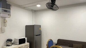 A compact kitchenette with a microwave, refrigerator, and a small white cabinet. - Steve Lady Hostel (Bangkok)