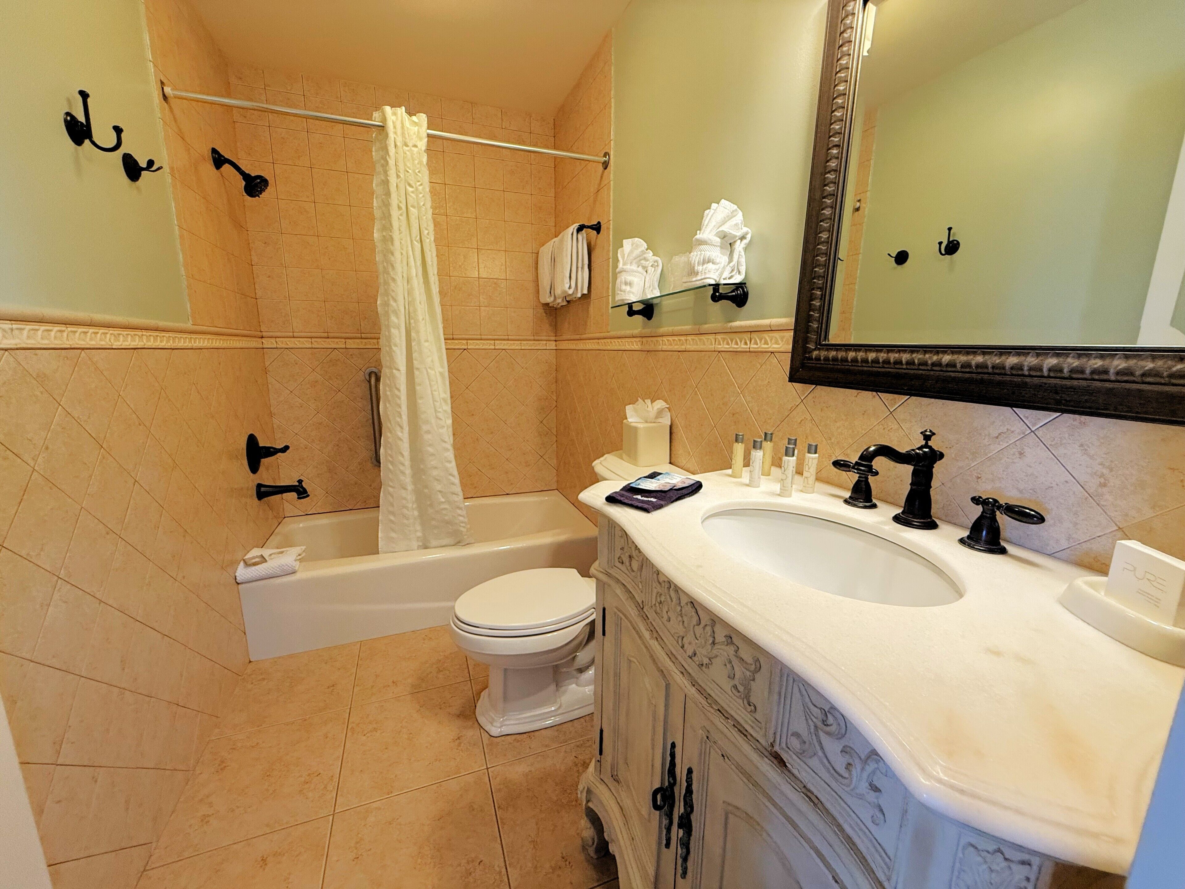 A bathroom with a bathtub, toilet, sink, and a mirror.
