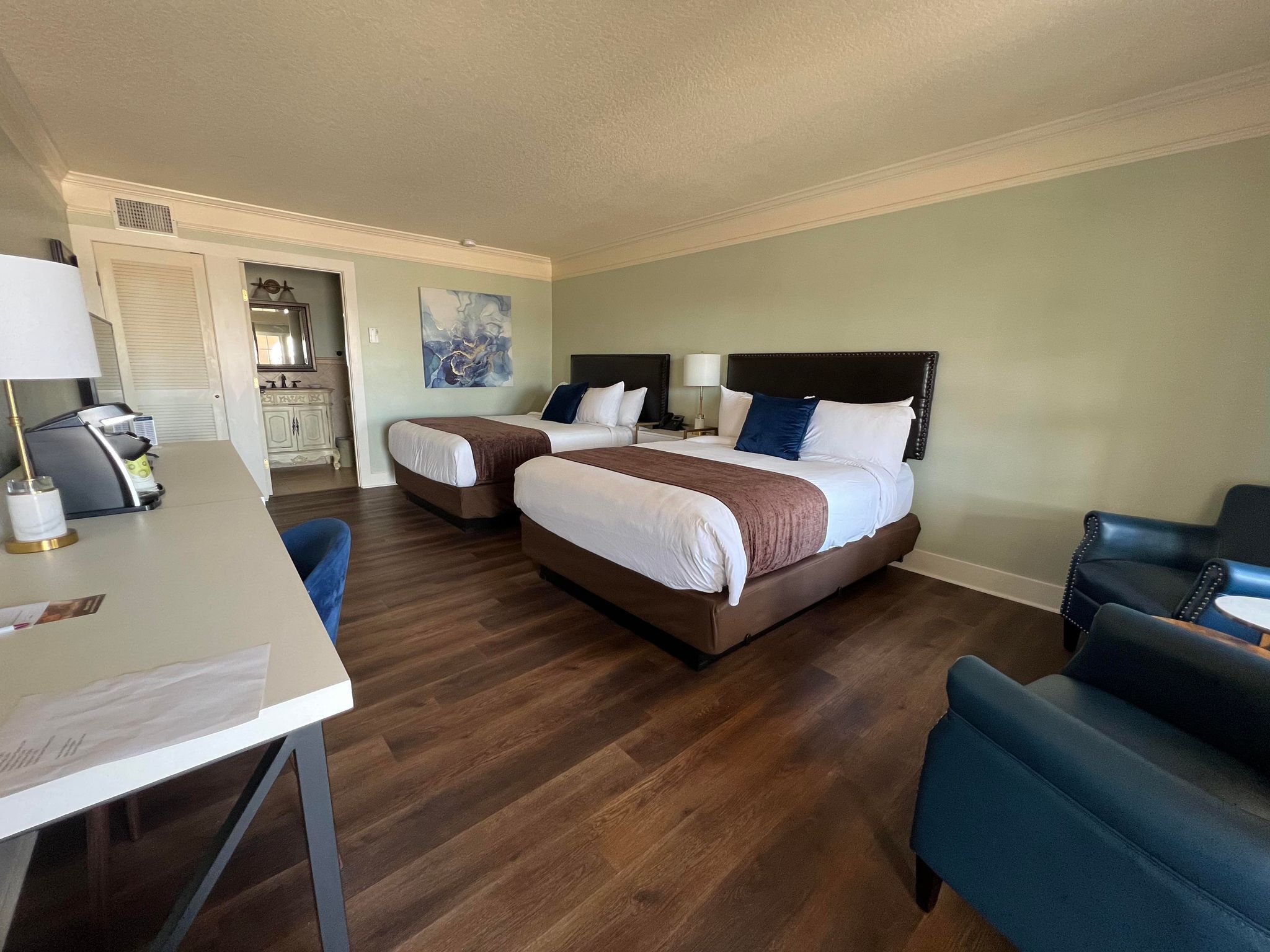 A hotel room with two beds, a desk, and a chair.