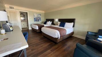 A hotel room with two beds, a desk, and a chair.