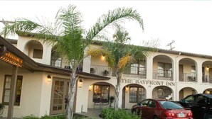 A hotel with a central courtyard, palm trees, and a red car parked in front.