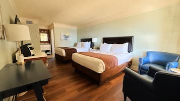 A hotel room with a large bed, a desk, a chair, and a small table.