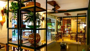 Une chambre d’hôtel moderne dotée d’une cloison en verre, de meubles en bois et de divers éléments décoratifs, notamment des plantes et un globe terrestre.