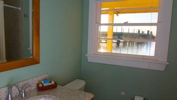Un baño con lavamanos, inodoro y ventana con vistas a un puente y al agua.