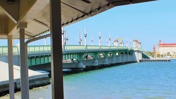 A waterfront view with a green bridge, a dock, and buildings in the background.