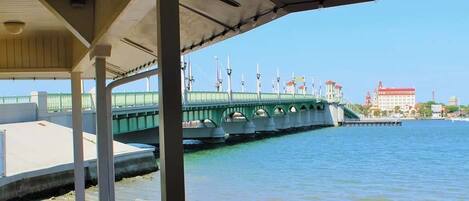 A waterfront view with a green bridge, a dock, and buildings in the background.