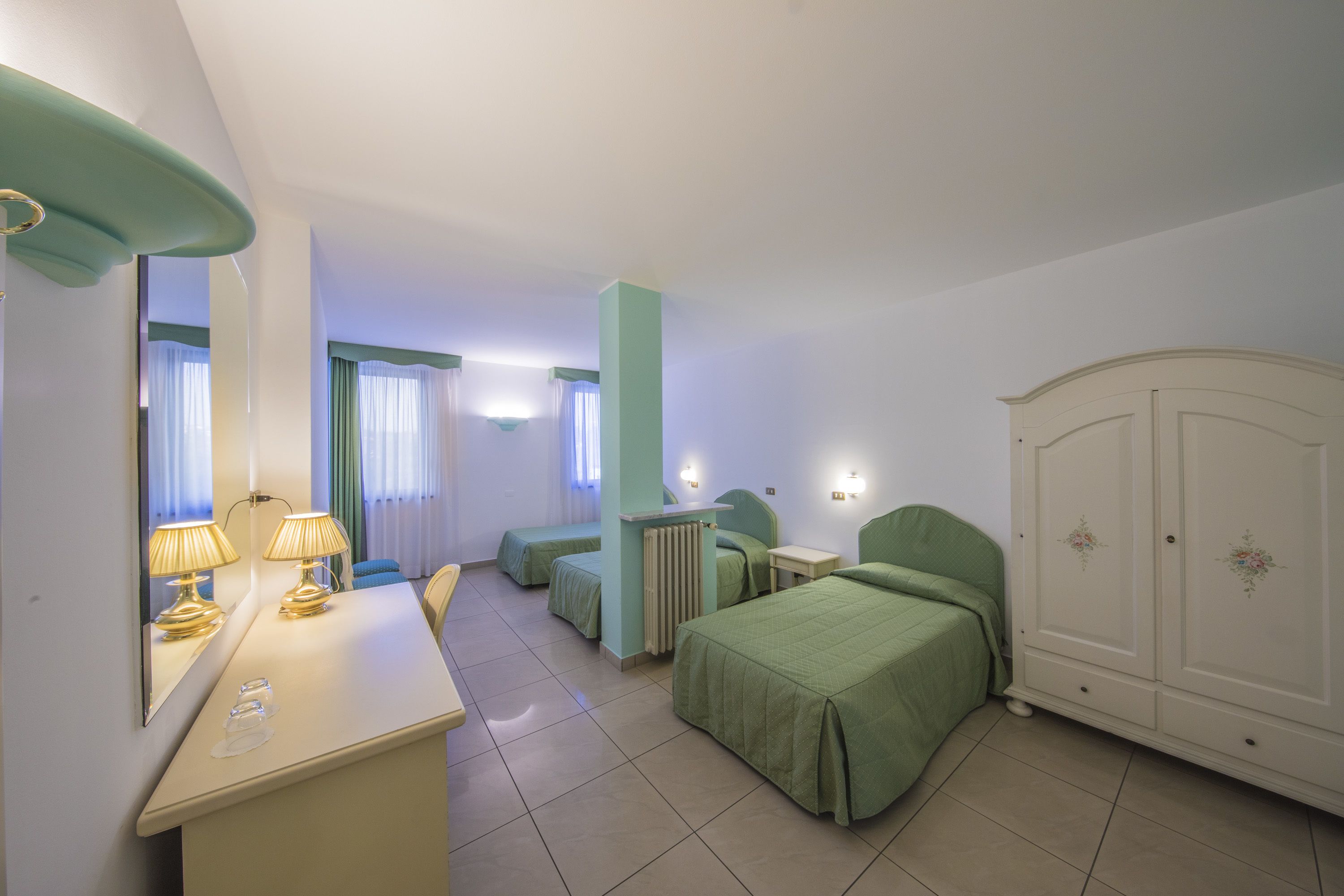 Een hotelkamer met een bed, een bureau met lamp, een kledingkast en een radiator.