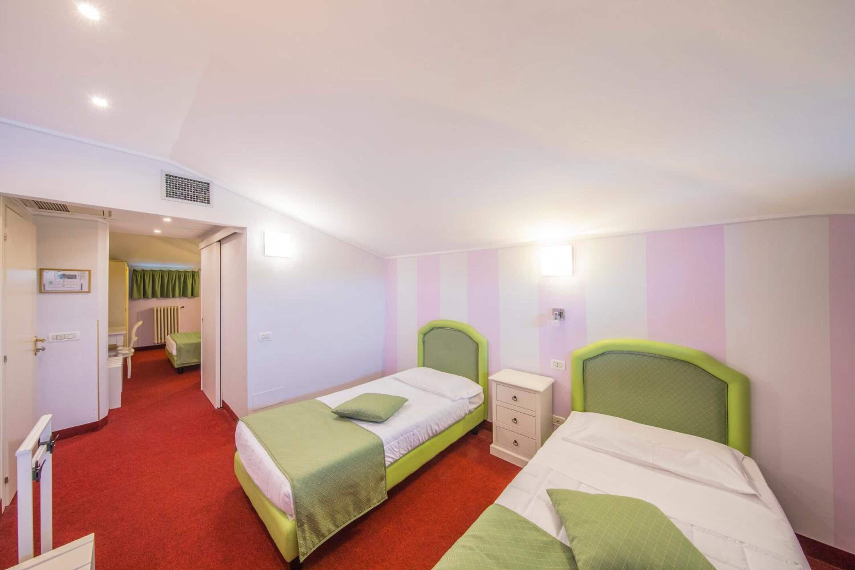 Une chambre d’hôtel avec deux lits simples, une petite table de chevet, une chaise et un radiateur.