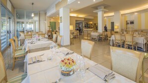 A restaurant with multiple dining tables set for guests, featuring white tablecloths, neatly arranged cutlery, and a centerpiece of flowers. - Hotel Ristorante Continental (Osio Sotto)