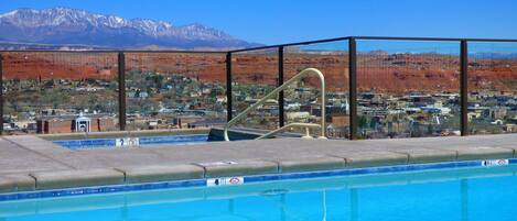 Una piscina con vistas a un pueblo y montañas al fondo.
