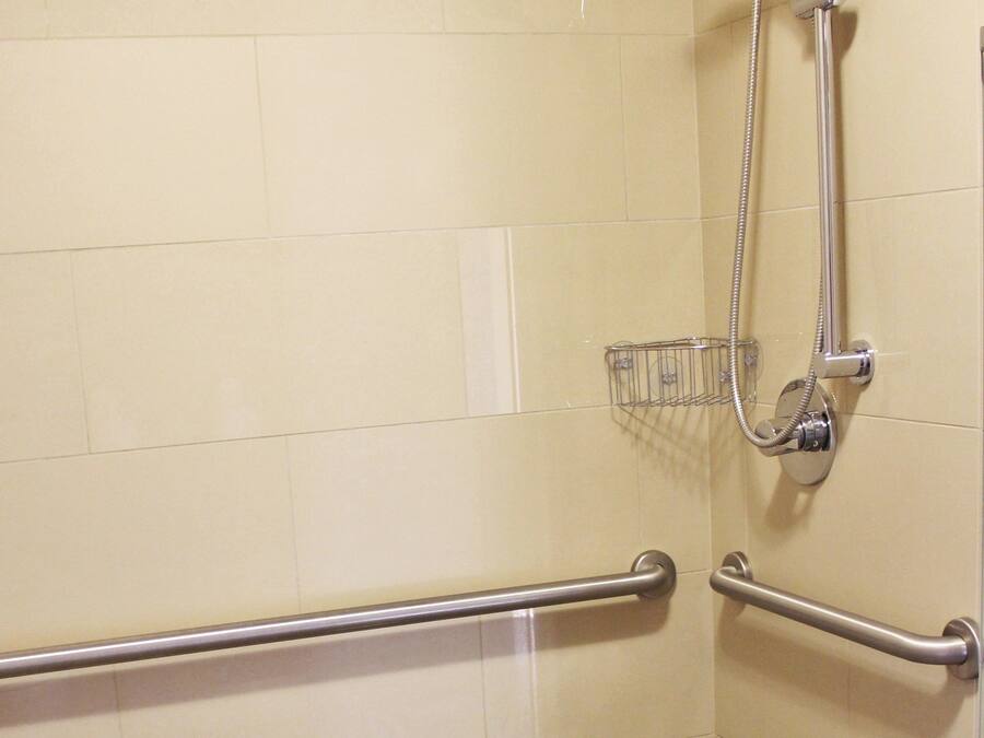 Un espace douche équipé de barres d'appui et d'un pommeau de douche amovible.