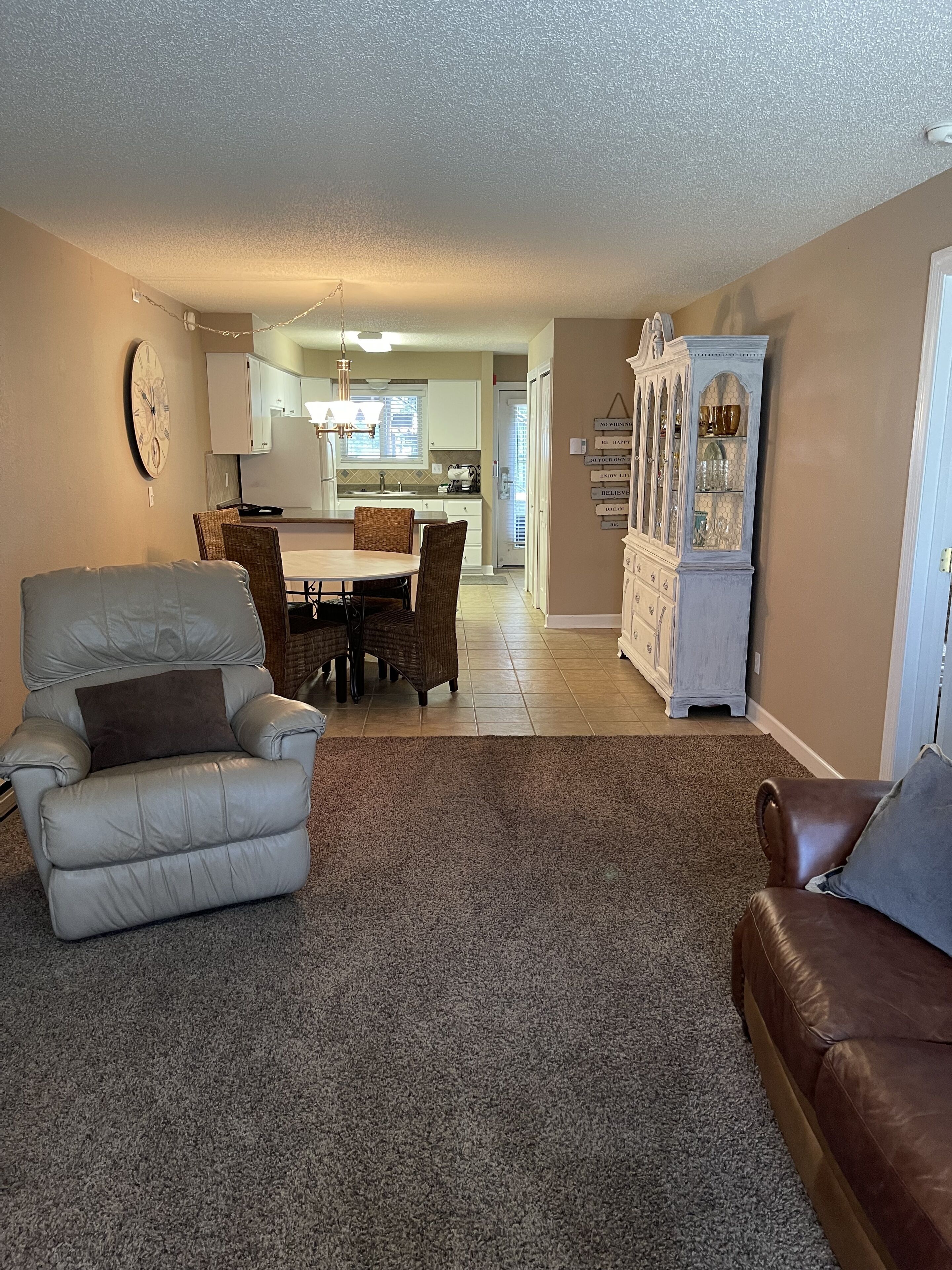 A living room with a gray leather sofa, a brown leather couch, and a dining area with a table and chairs.