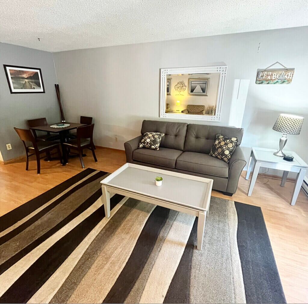 A living room with a sofa, coffee table, and a dining area with chairs and a table.