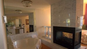 A spacious bathroom with a large bathtub, a mirror, and a fireplace.