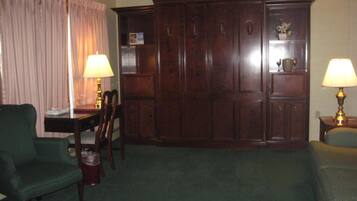 A room with a green armchair, a wooden cabinet, and two lamps.