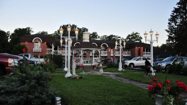 A gazebo with multiple light fixtures, surrounded by a well-maintained lawn and potted plants.