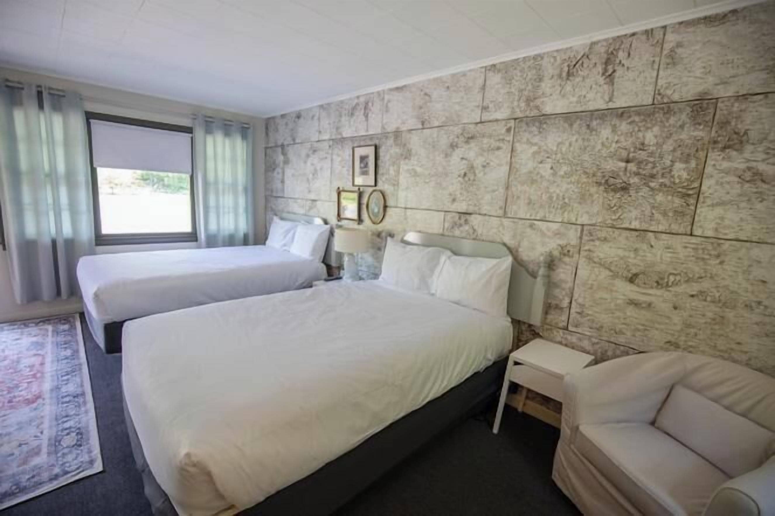 Habitación de hotel con dos camas, un sofá, una mesita de noche y una ventana con cortinas.