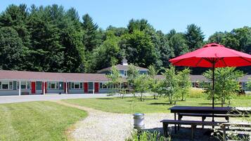 A motel with a red umbrella, a picnic table, and a gravel path.