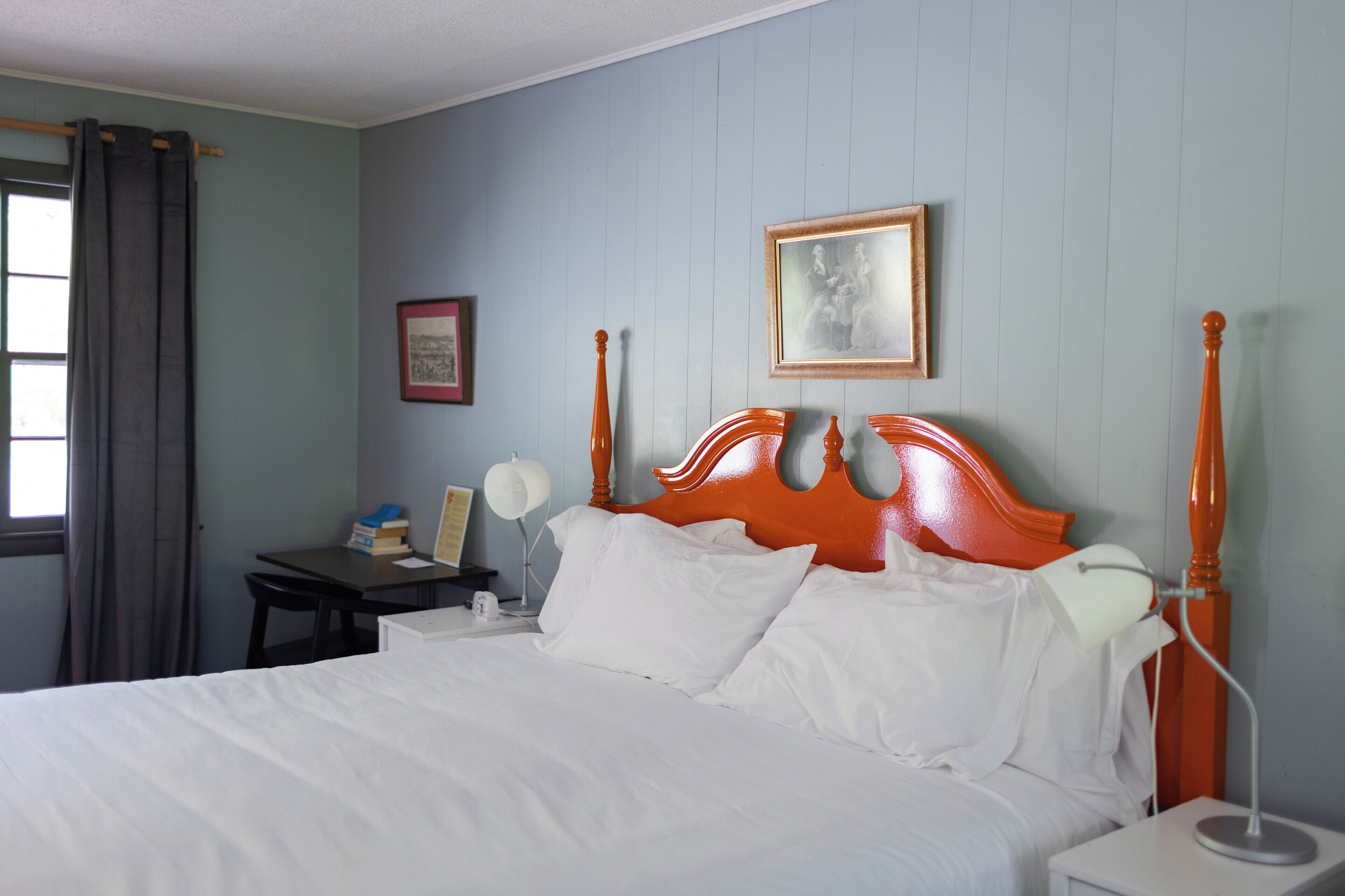 A neatly made bed with white linens, a wooden headboard, and a bedside table with a lamp.