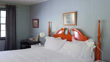 A neatly made bed with white linens, a wooden headboard, and a bedside table with a lamp.
